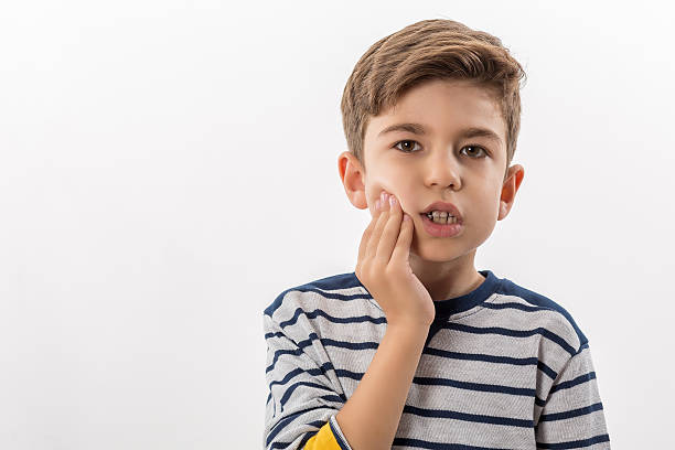 Young boy rubbing his jaw due to tooth pain.