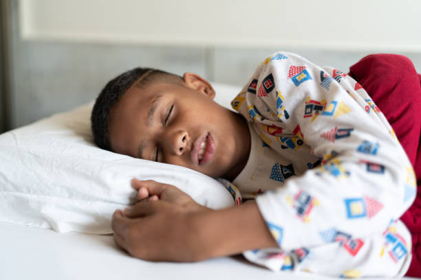 A young boy sleeps in his bed.