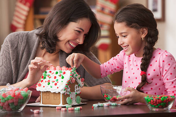 Mother and daughter building a gingerbread house.