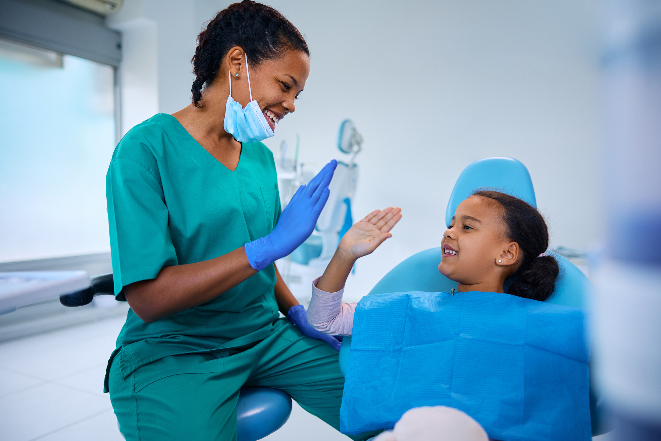 kid smiling and high fiving dentist at dentist appointment